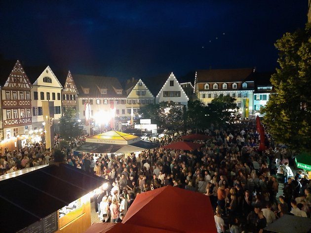 Der belebte Marktplatz mit Besuchern und Ständen bei Nacht