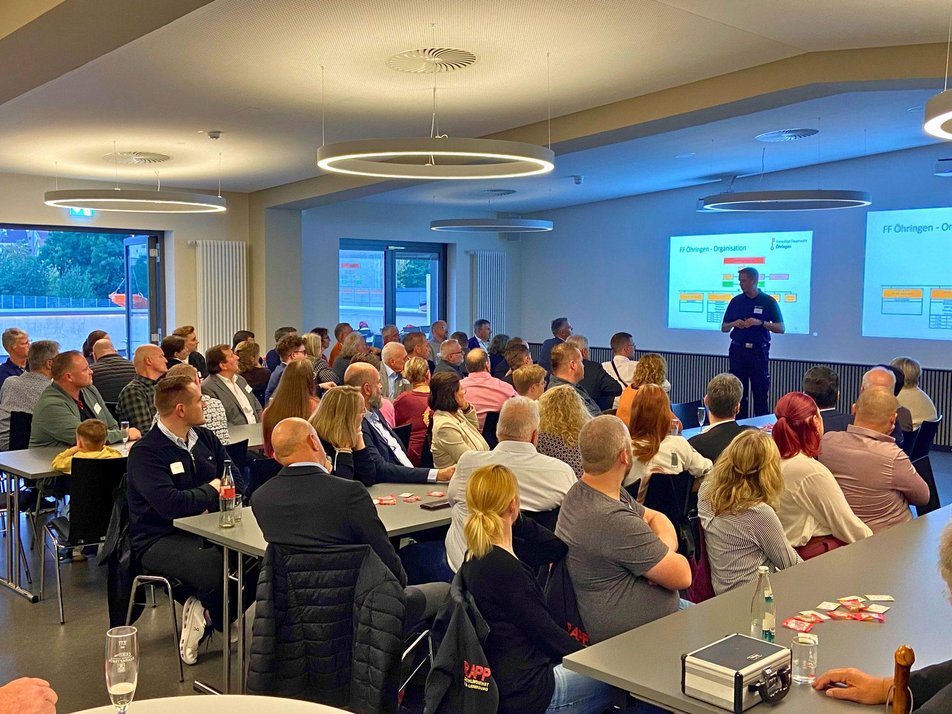 Teilnehmende des Wirtschaftsstammtisches hören Kommandant Pawellek bei Rede zu