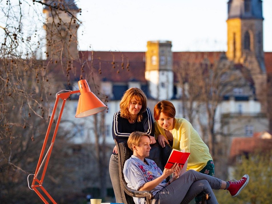 Drei Personen schauen gemeinsam in ein Buch